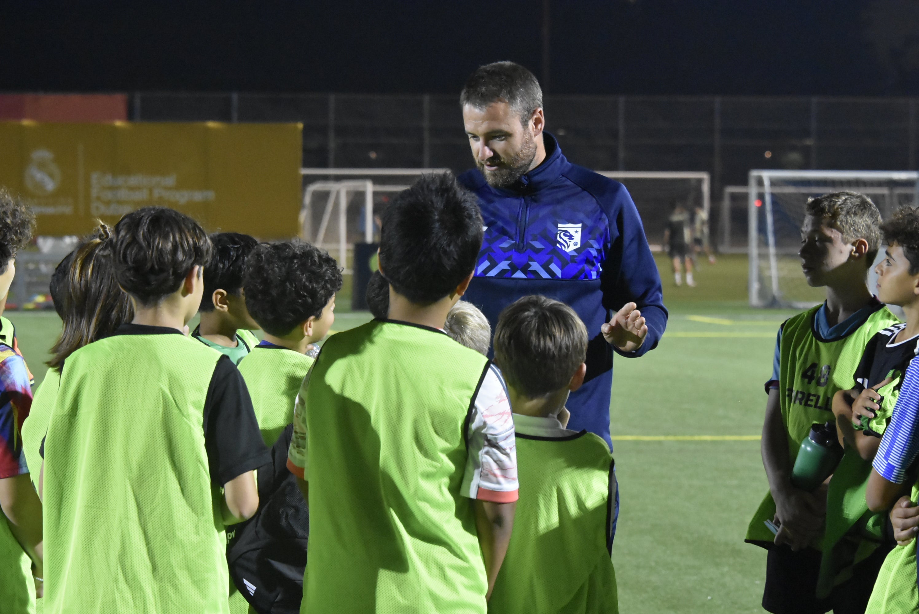 Football coach discussing training costs and programme fees with young players at a UK boarding school