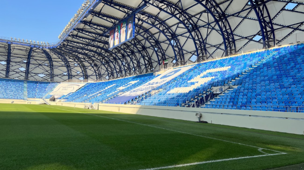Modern football stadium with blue seats and green pitch ready for a showcase event in Dubai