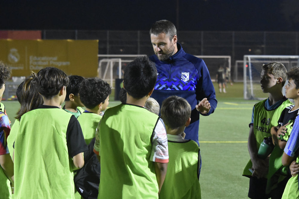 Football coach briefing young players during a training session at a UK boarding school