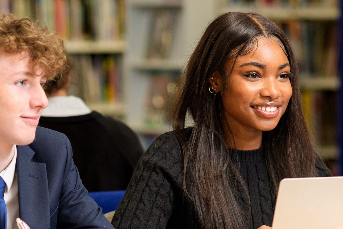 Two older pupils studying at a laptop in a school library